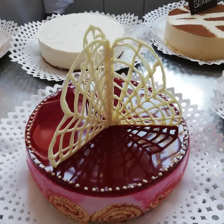 Torta con glaseado espejo de frambuesa y encaje de chocolate blanco.